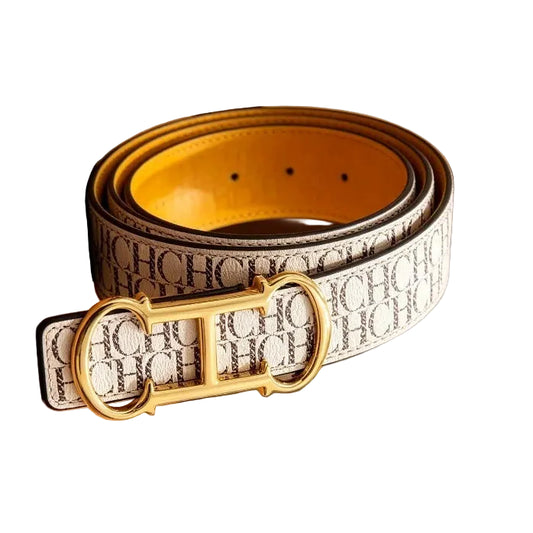 A white leather belt with a black script monogram pattern and a gold-tone buckle, displayed on a wooden counter inside a boutique setting.